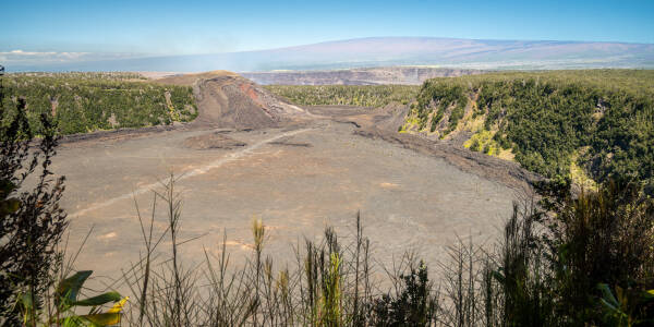 View from the rim of Kīlauea Iki crater at Volcanoes National Park in Hawaii, shows the narrow white hiking trail crossing the crater floor.