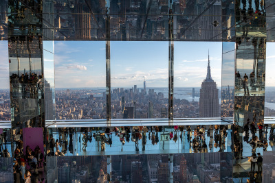 Mirrored people frame the lower Manhattan skyline in the many mirrored main gallery at One Vanderbilt.