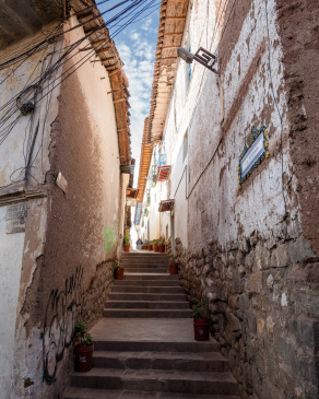 Sun shines down into a narrow curving alley in San Blas