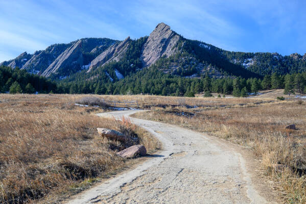 The Flatirons rise in a nest of pine trees behind a winding trail at Chautauqua Park in Bouolder, Colorado.