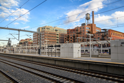 Brick buildings with a smokestack and water tower sit next to the tracks at Union Station in Denver, Colorado.