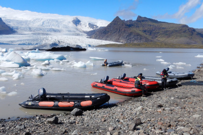 Bright zodiac inflatable boats wait for passengers on the shore of FjallsÃ¡rlÃ³n glacier lagoon in Iceland.