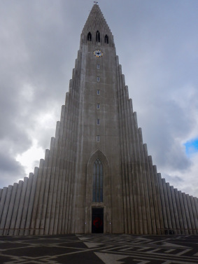 Thin stone columns rise into a cloudy Reykjavik sky around the main tower of HallgrÃ­mskirkja.