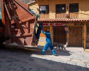 Dog follows garbage truck in Ollantaytambo hoping for a treat.