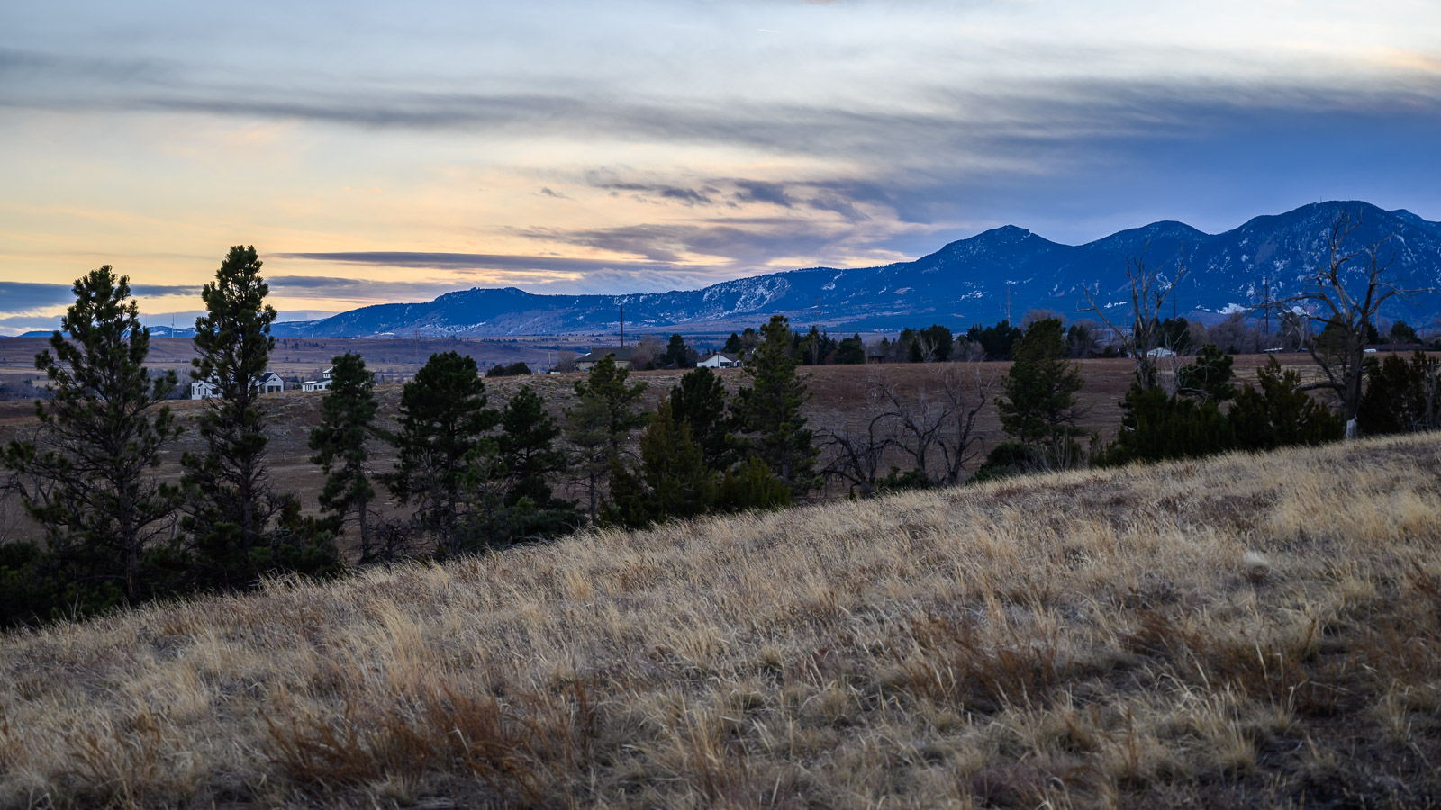 The sun retreats behind the Flatirons with its blanket of clouds at Legion Park in Boulder, Colorado.