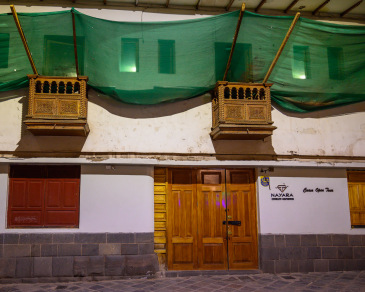 Shop front with green awning and red windows on a street near Plaza de Armas in Cusco