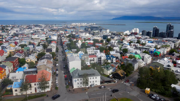 The colorful west end of ReykjavÃ­k shines against the sea during a break in the clouds as seen from atop HallgrÃ­mskirkja.