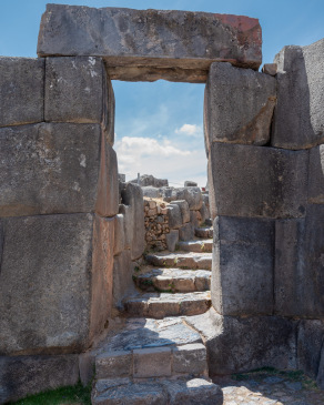 A doorway made of large stones leading to a curving stairway at SacsayhuamÃ¡n