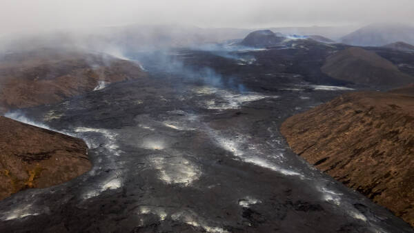 Fresh black lava puffs white clouds of smoke as it cools on top of Fagradalsfjall volcano in Iceland.