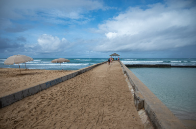 Sandy walkway recedes into a blue ocean at Kuhio Beach near Waikiki in Honolulu, Hawaii