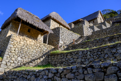 Small thatched stone buildings sit on the agricultural terraces near the entrance to Machu Picchu.
