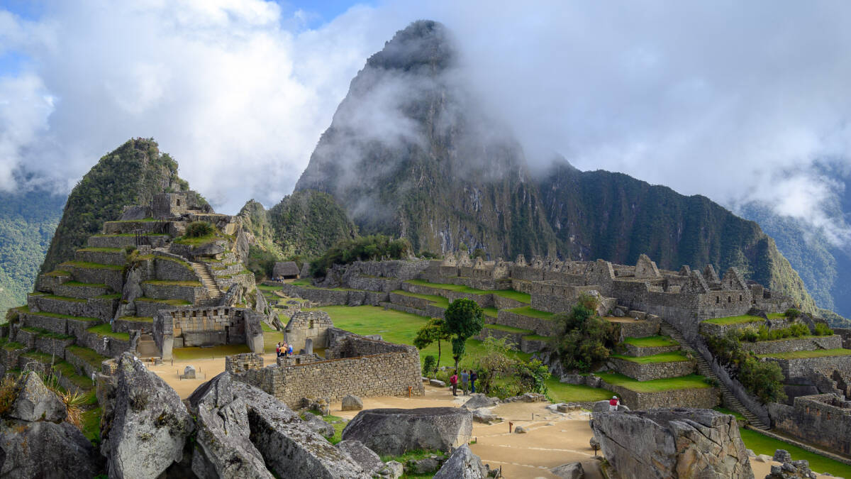 The central plaza of Machu Picchu shines emerald green in front of its mountain backdrop.