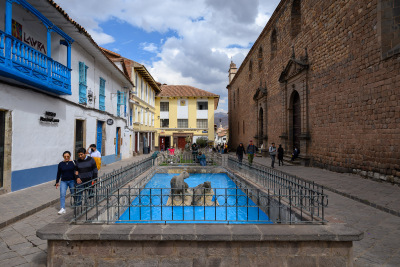 Blue water surrounds puma figures in a fountain in central Cusco.