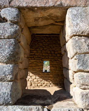 Peering through aligned windows into a reconstructed hut at Machu Picchu