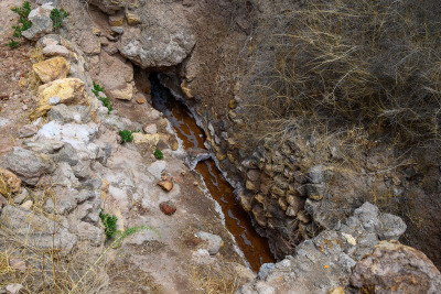 Small channel of mineral rich brown water feeding the evaporation pools at Marasal.