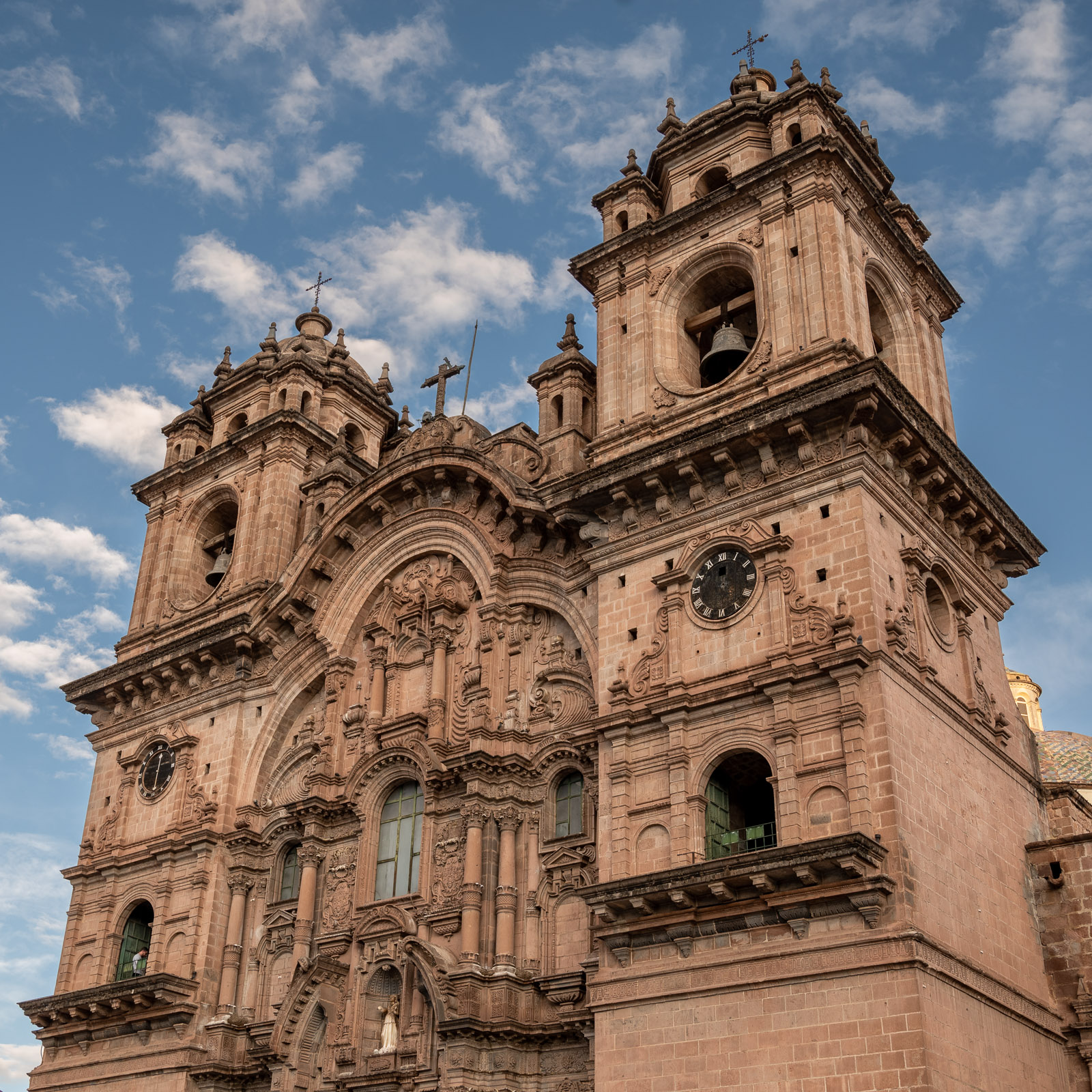 Ornate stone church towers rise into a blue sky in Cusco
