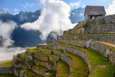 Two people watch the last remnants of the morning fog rise into the sky at Machu Picchu.