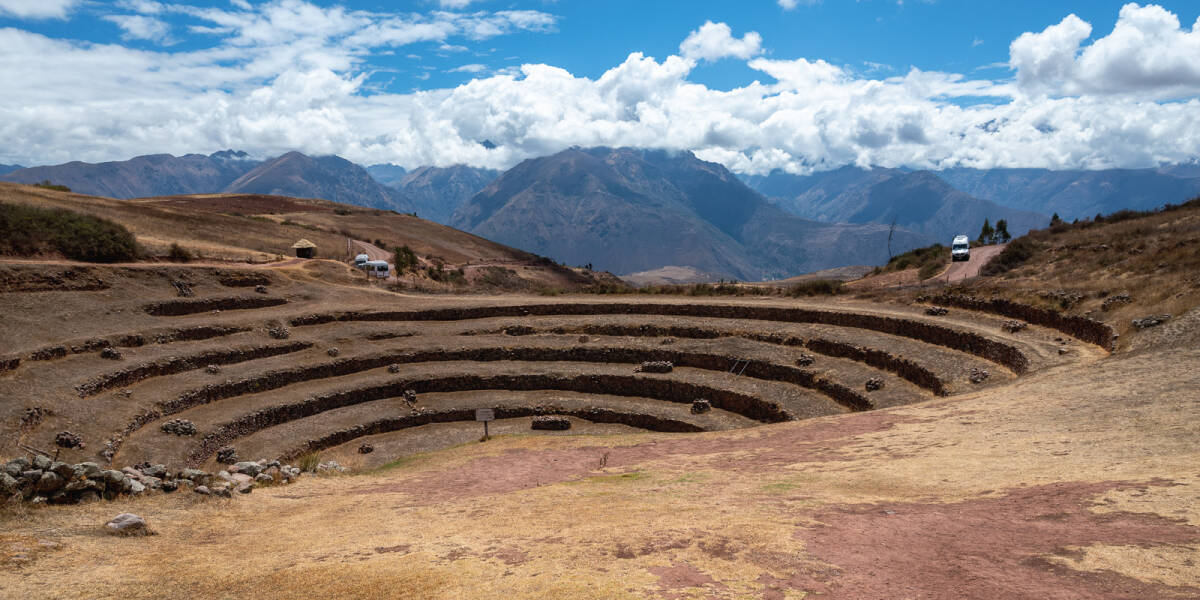 The cloud covered Andes stretch out behind a circle of Incan terraces being restored at Moray.