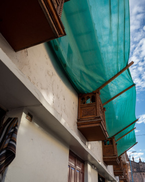 Transparent green awning draped across balconies In Cusco
